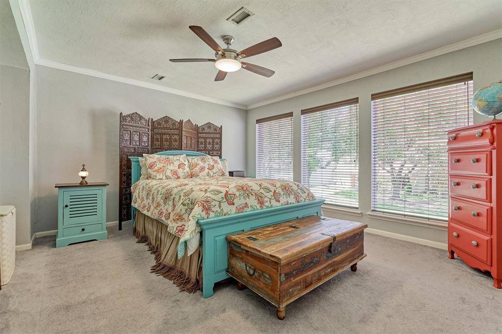 Large primary bedroom with long walk-in closet, crown molding and plush carpeting. Enjoy views of the outdoors with the expansive windows!