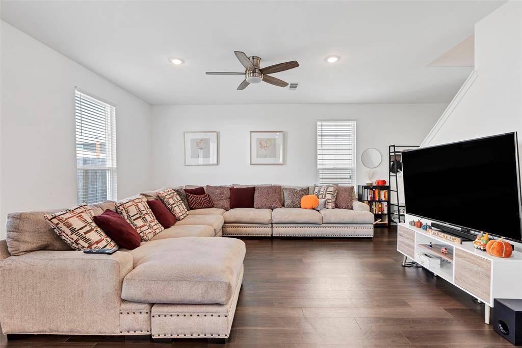 The living room has an abundance of natural light and a ceiling fan for a comfortable environment ideal for relaxing and entertaining.