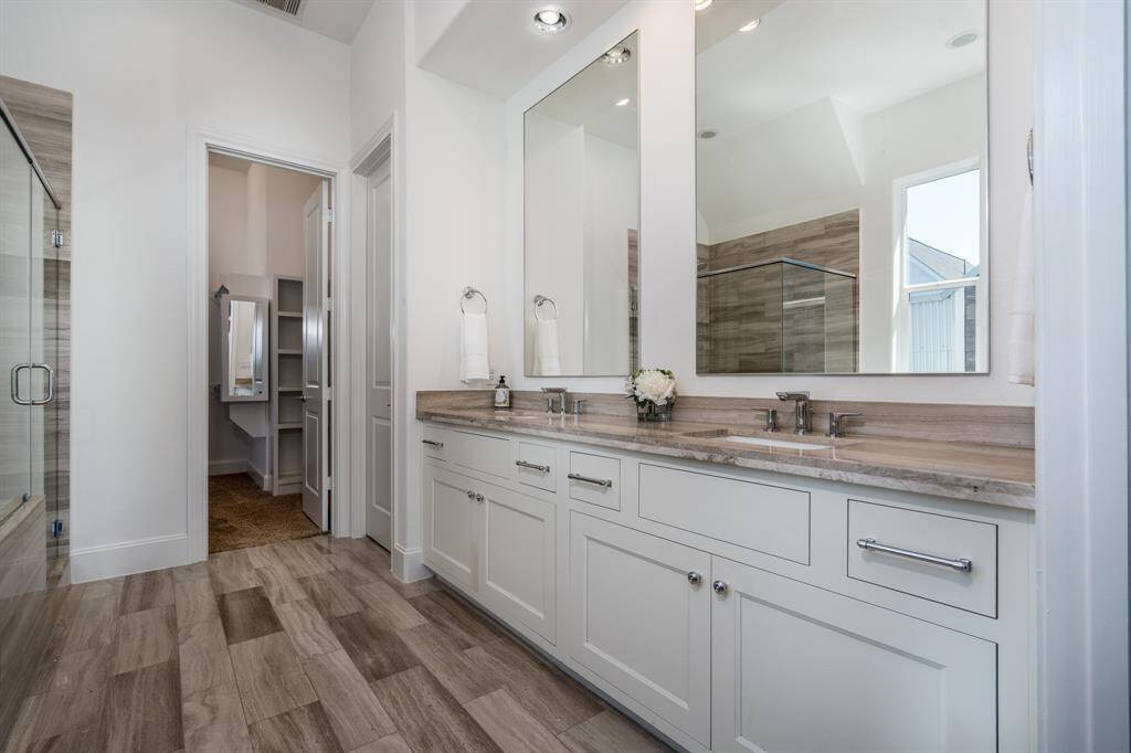 The primary bathroom has dual vanities, wood-look tile and plenty of cabinet space.
