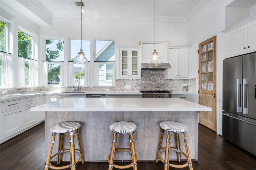 The kitchen is the center of this home and a wonderful gathering place. Notice the tall ceilings with crown molding and the giant windows surrounding the back of the kitchen.