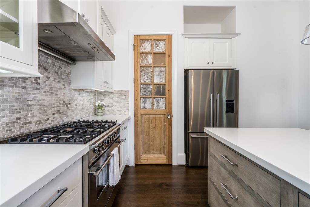 Notice the mosaic tile backsplash made of natural stone and custom pantry door.