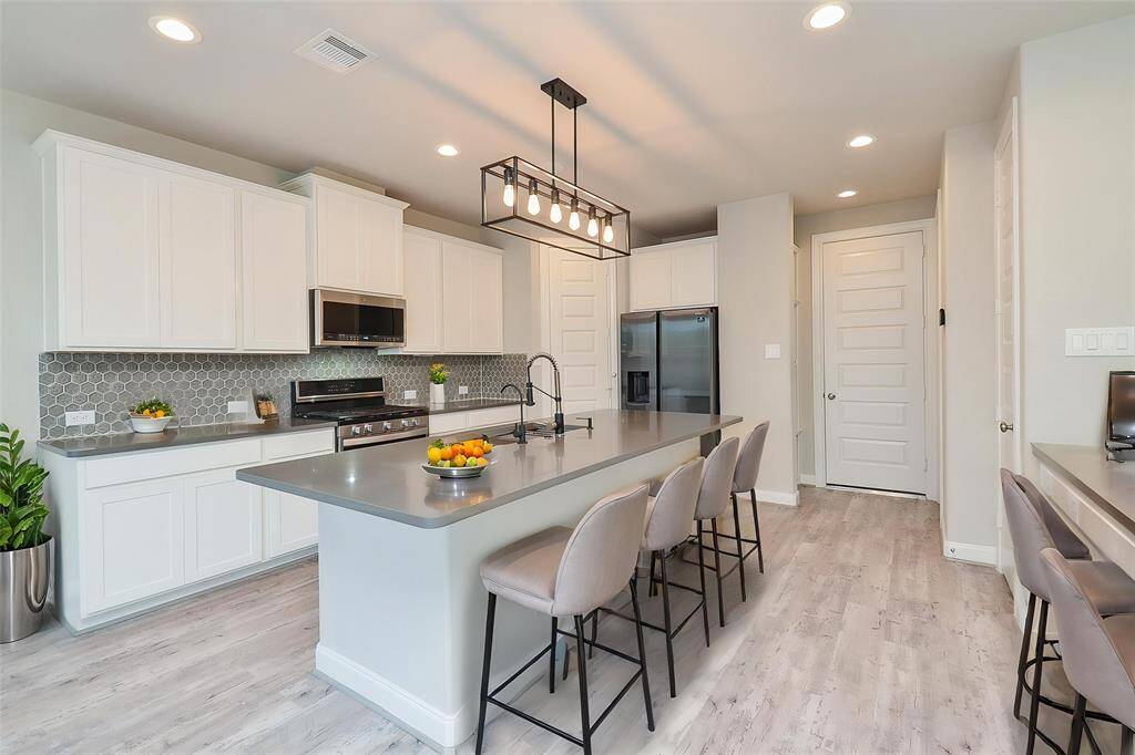 Imagine preparing meals on the expansive, sleek countertop island, perfect for casual dining or entertaining guests.