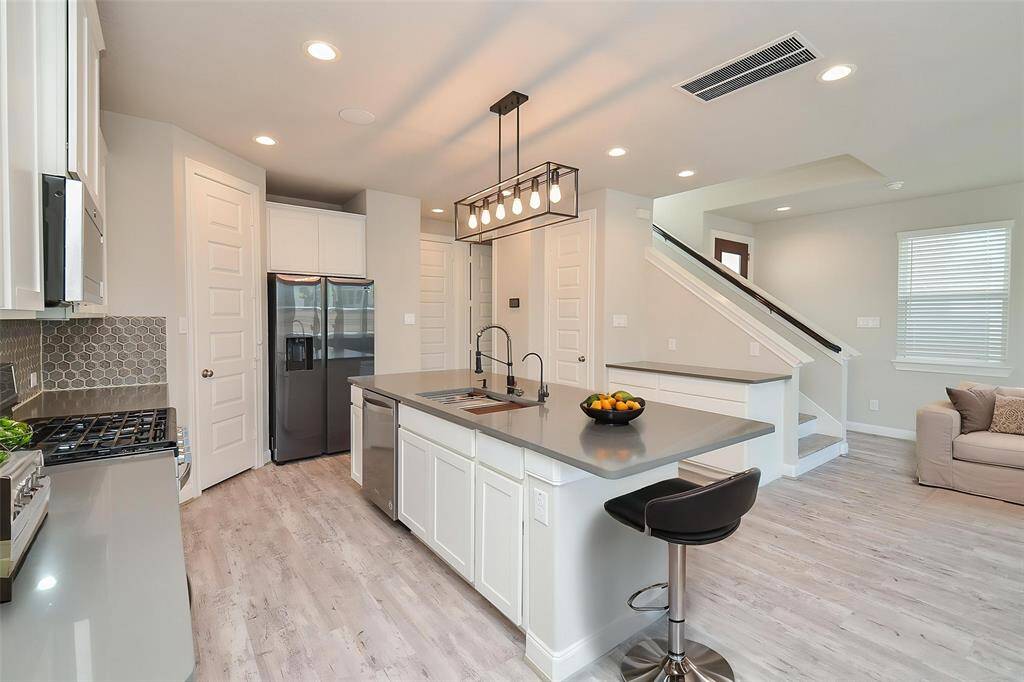 The contemporary lighting fixture above the island adds a touch of modern elegance. Notice the stylish backsplash that complements the clean lines of the design.