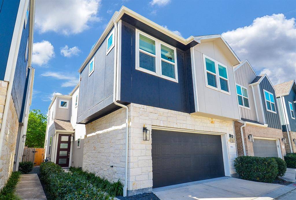 The exterior showcases a striking contrast of dark siding and light stone accents, leading to a convenient attached garage.