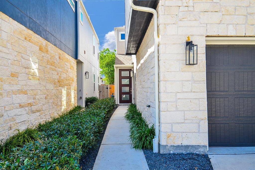 This inviting walkway, framed by lush greenery leads you to a stylish front door.