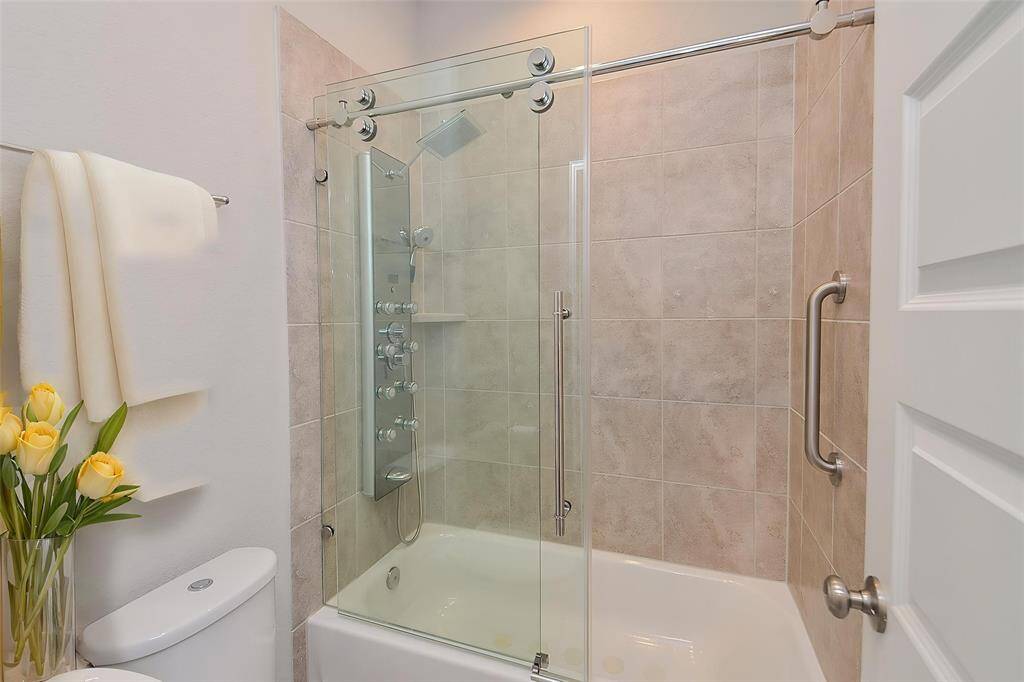 Step into this stylishly appointed bathroom featuring a modern, frameless sliding glass bathtub door.