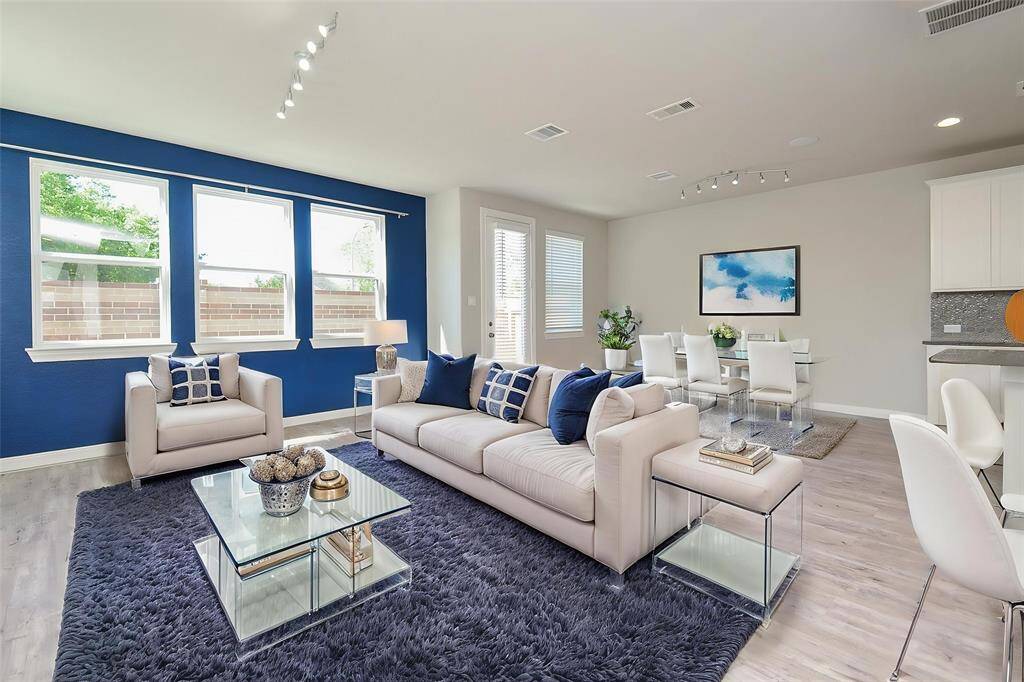 Natural light floods the space, highlighting the seamless connection between the living room, dining area, and kitchen.