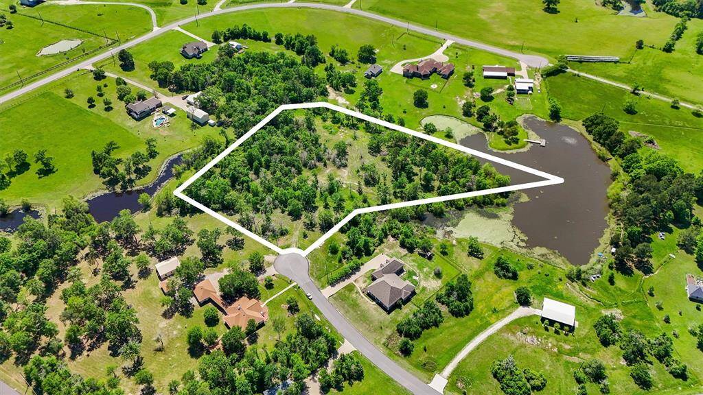 Stunning aerial view of a premium 5-acre homesite, ideally positioned at the end of an exclusive cul-de-sac amidst a collection of custom luxury estates. This partially cleared property offers an exceptional opportunity to design a private, upscale residence surrounded by mature trees, serene natural landscapes, and picturesque water features. With ample space for a grand estate, resort-style pool, guest quarters, or equestrian amenities, this expansive lot delivers both elegance and tranquility.