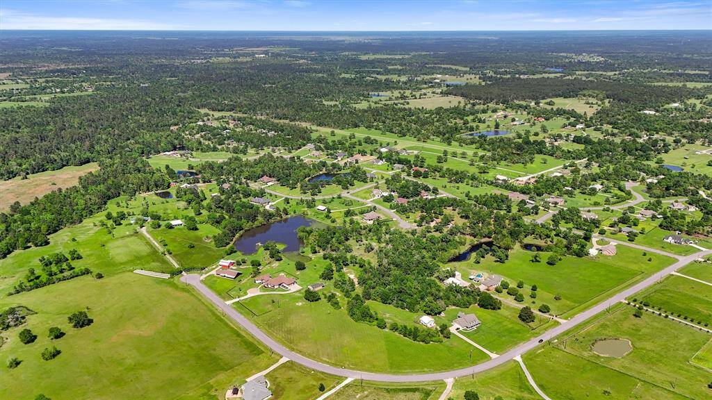 This aerial photo showcases a spacious, scenic rural area dotted with homes, surrounded by lush greenery and small ponds. Ideal for those seeking tranquility and natural beauty in a community setting.