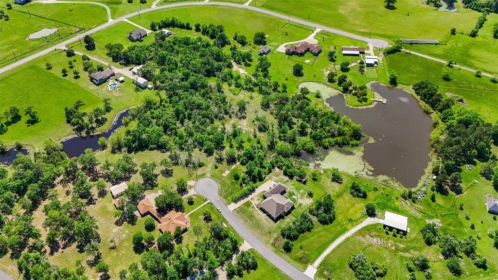 Breathtaking aerial view of a partially cleared 5-acre homesite nestled at the end of a peaceful cul-de-sac in a private, scenic countryside setting. Surrounded by mature trees, neighboring custom estates, and tranquil water features, this prime property offers the perfect blend of seclusion and natural beauty. Ideal canvas for building your dream home with ample space for additional structures, gardens, or a private retreat.