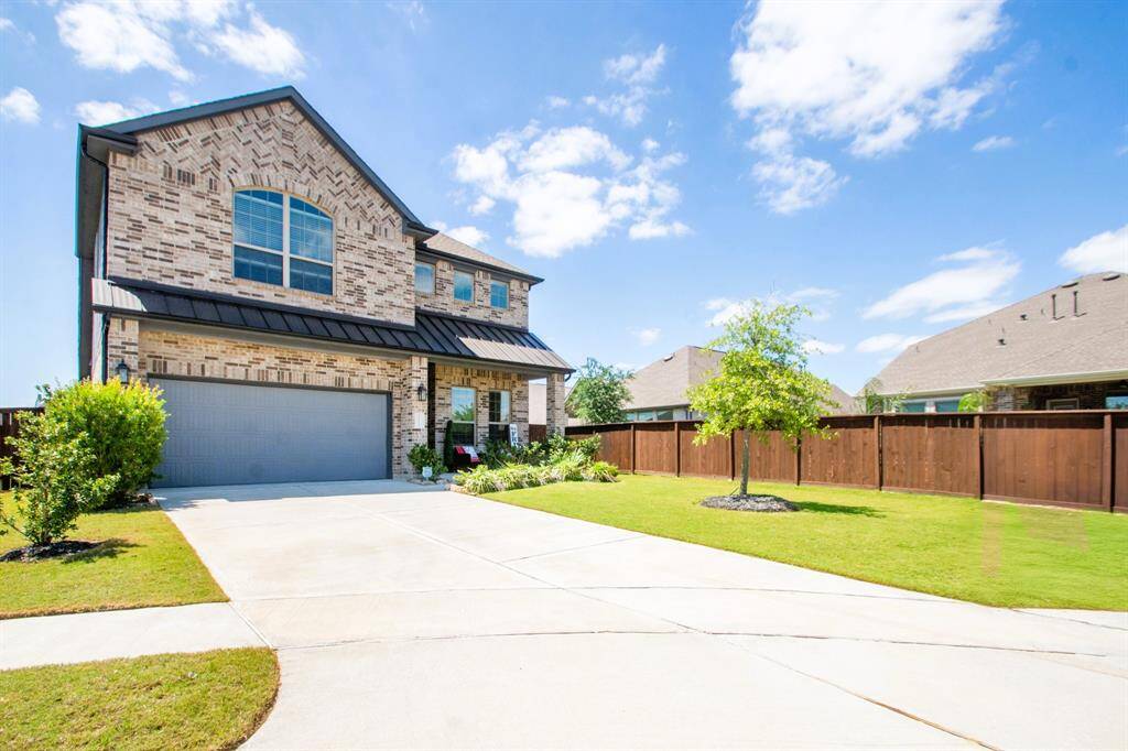 This is a modern two-story brick home, nestled in a cul-de-sac, has a spacious driveway and a well-maintained front yard. It features a two-car garage and a fenced backyard, offering privacy and outdoor space. The large windows provide ample natural light inside.