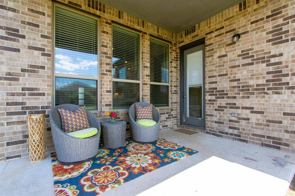 Cozy covered back patio with brick walls, features a perfect space for outdoor furniture and a grill. Ideal for relaxing and enjoying outdoor views, including watching your children play on the backyard playground!