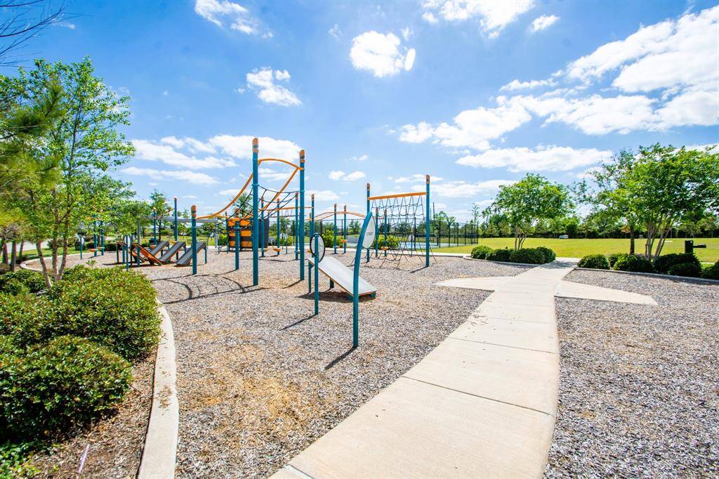 Another angle of the many spacious, well-maintained playgrounds with climbing structures and slides, set in a park surrounded by greenery. Perfect for families and outdoor activities.