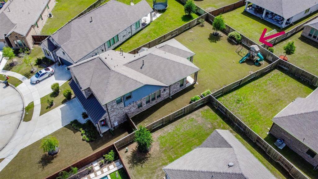 This aerial photo shows the spacious fenced backyard, featuring a playset. The property is located in a quiet cul-de-sac with nearby houses and well-maintained lawns.
