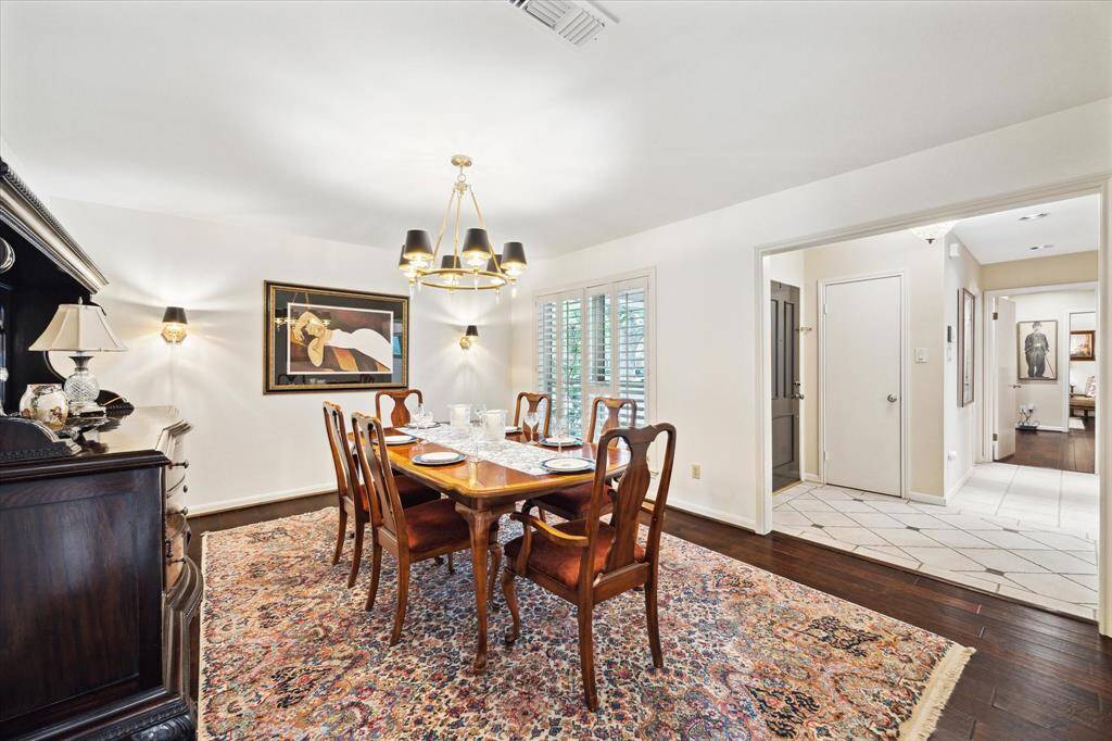 The dining room is well-lit with natural light from large windows and has hardwood floors, creating a warm and inviting atmosphere.