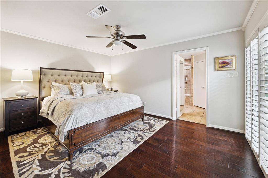 This primary bedroom is bright and spacious featuring wood floors and doors to the patio.