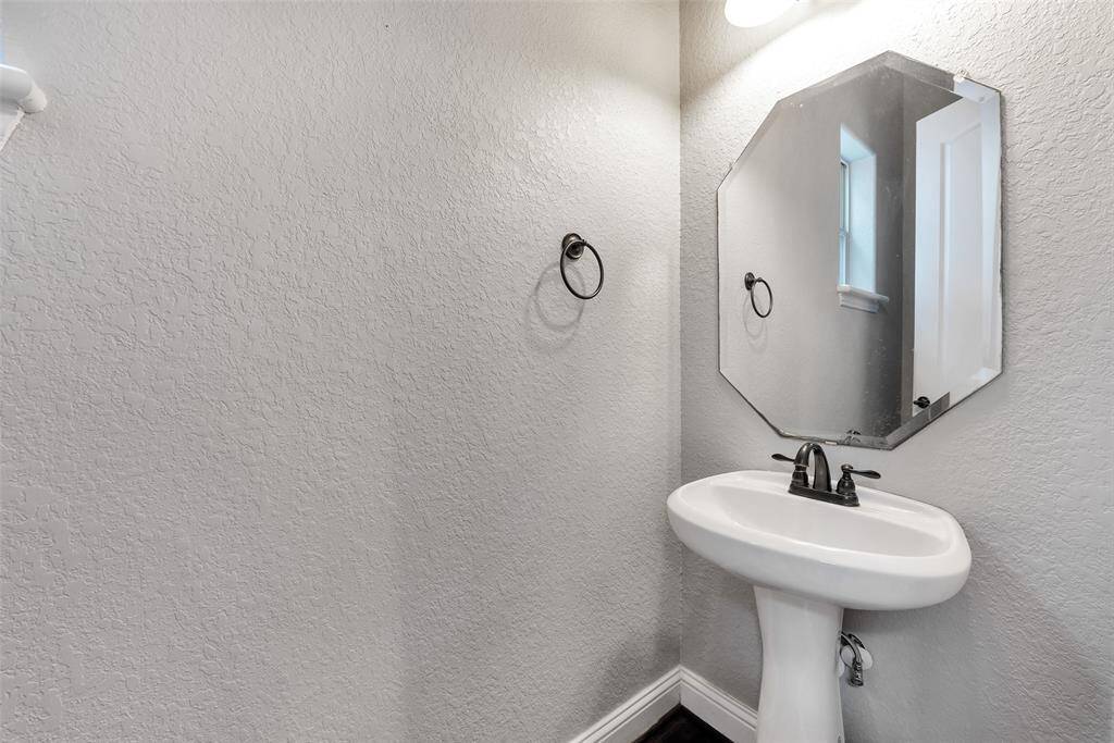 The half bath on the second floor features a pedestal sink and hardwood floors.