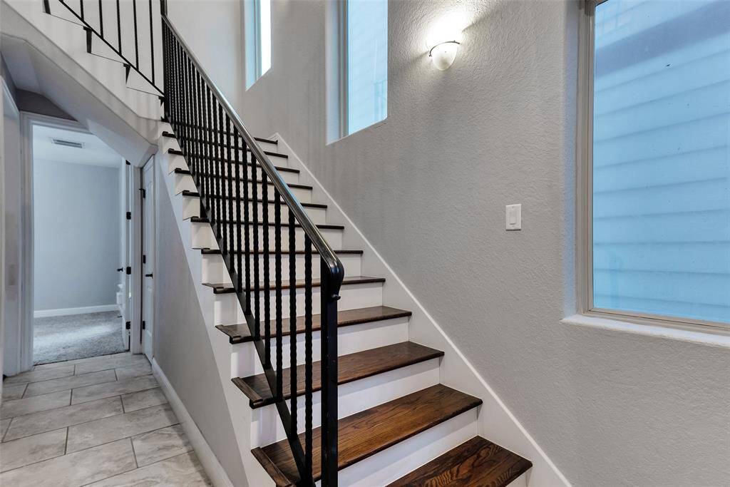 On the same floor as the garage, there is a secondary bedroom with an ensuite full bath and a walk-in closet on the first floor. The door leads to one of two secondary bedrooms.