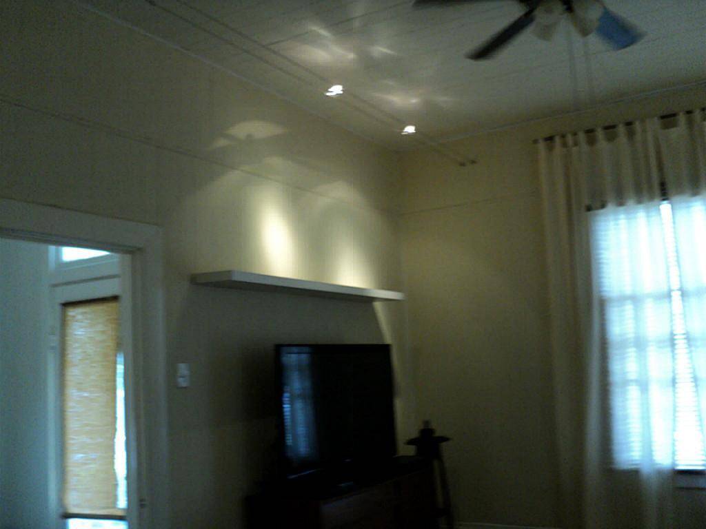 living room looking into entry. Note halogen track lighting and ceiling fan