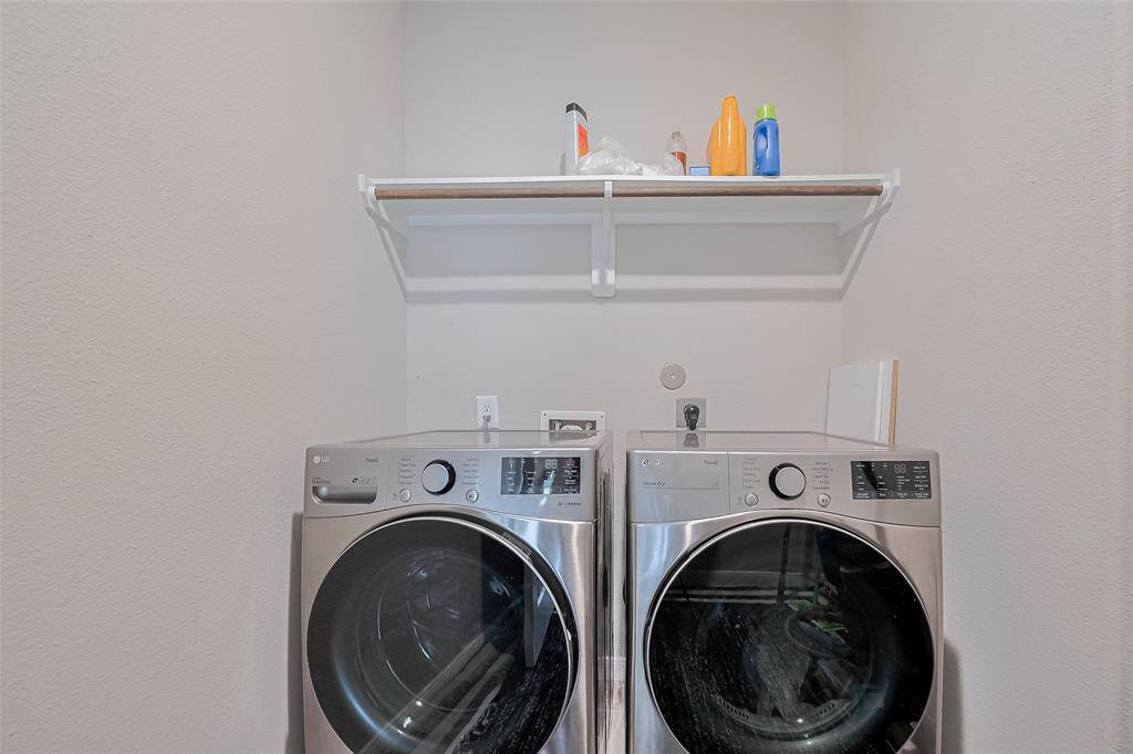 Efficient and practical, the laundry room includes a mounted rack above the washer and dryer—ideal for keeping supplies organized and within easy reach.