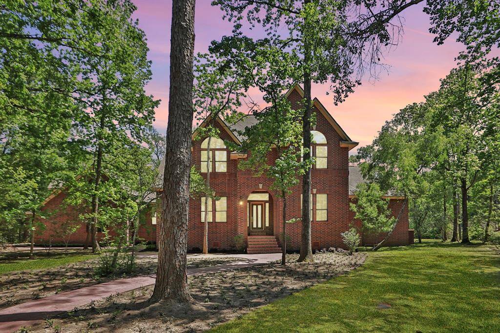 This photo showcases a stunning two-story brick home tucked away on 1.88 acres