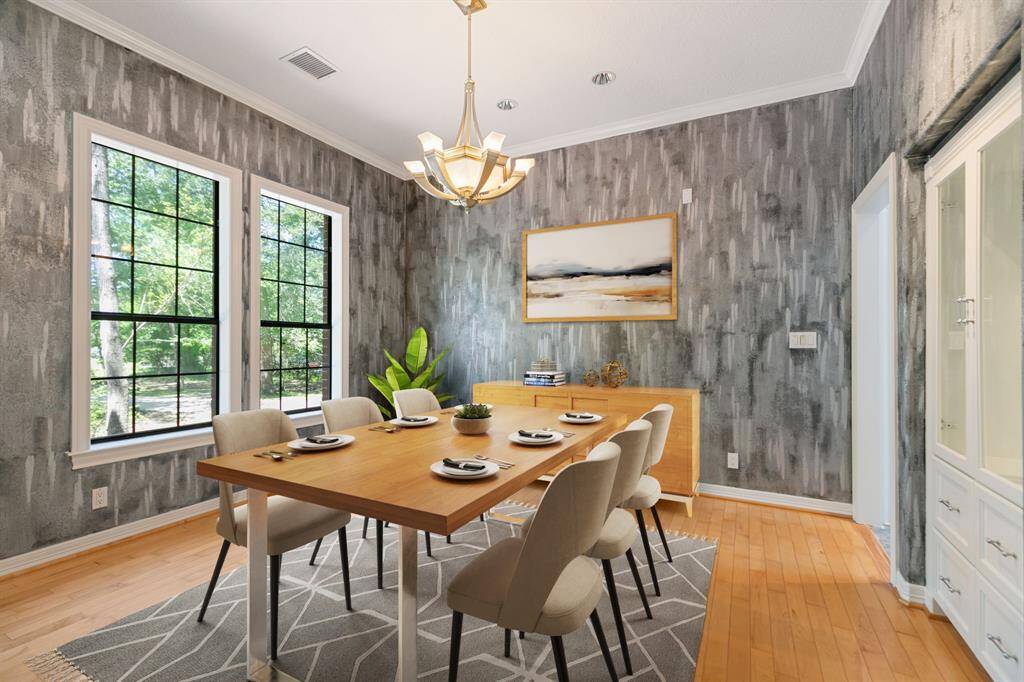 Virtually staged. This dining room features a modern design with textured gray walls, large windows offering natural light & a stylish chandelier while light wood flooring & a built-in cabinet enhance functionality.