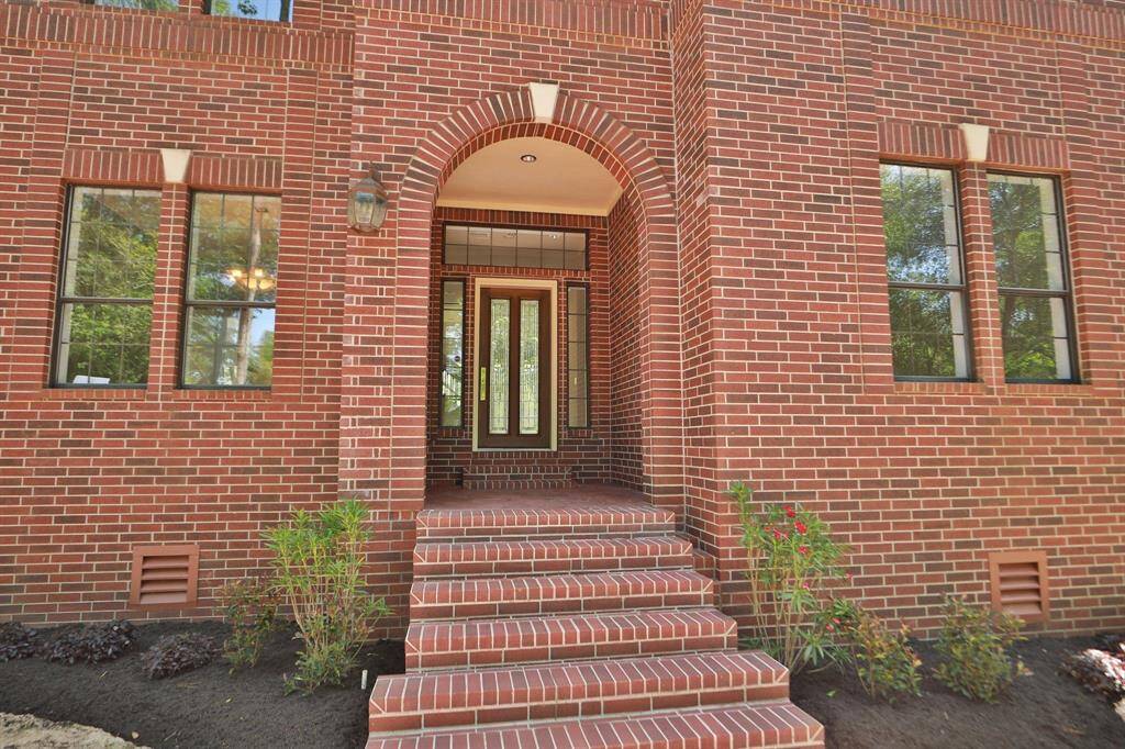 Classic brick exterior with a welcoming arched entryway, featuring large windows and a set of steps leading to an elegant front door.