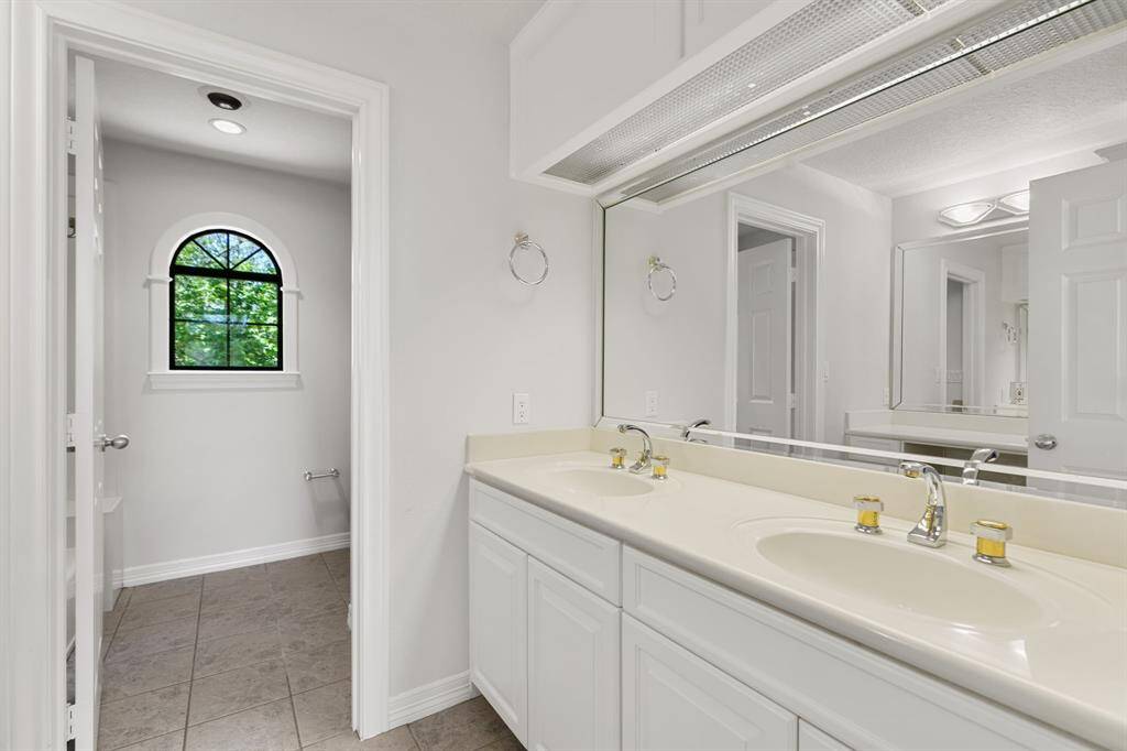Double sinks in one of the secondary bathrooms upstairs with a vanity area.