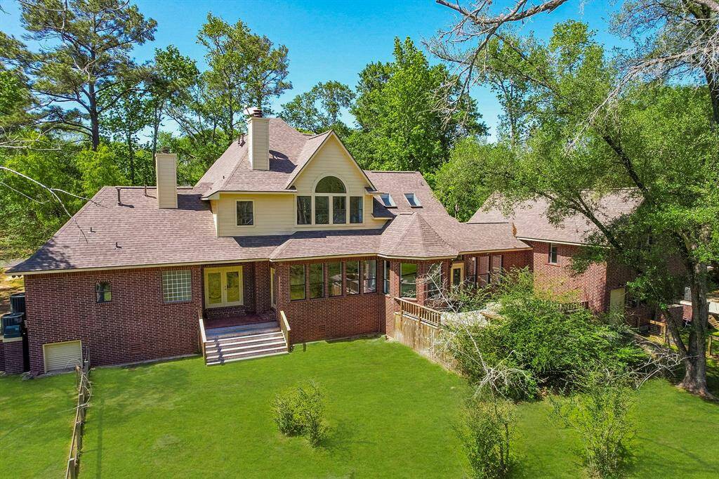 View of the back of the home with its extensive deck as well as a covered area off of the primary bedroom perfect for outdoor enjoyment.