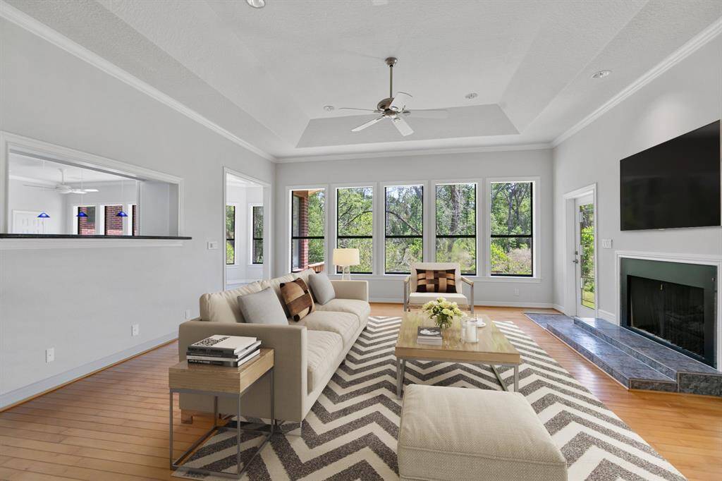 Virtually staged.Bright and spacious living area with hardwood floors, a ceiling fan, and ample natural light. Features a cozy fireplace and easy access to outdoor space through a glass door. Ideal for comfortable living and entertaining.