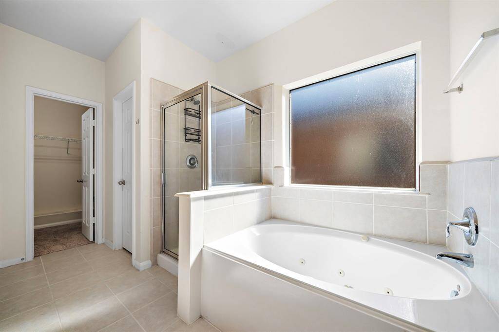 The primary bath is a serene retreat, featuring a spacious spa jetted tub and an expansive walk-in shower with glass enclosures. Dual vanities enhance functionality, while elegant finishes create a luxurious atmosphere. Direct access to the walk-in closet offers added convenience.