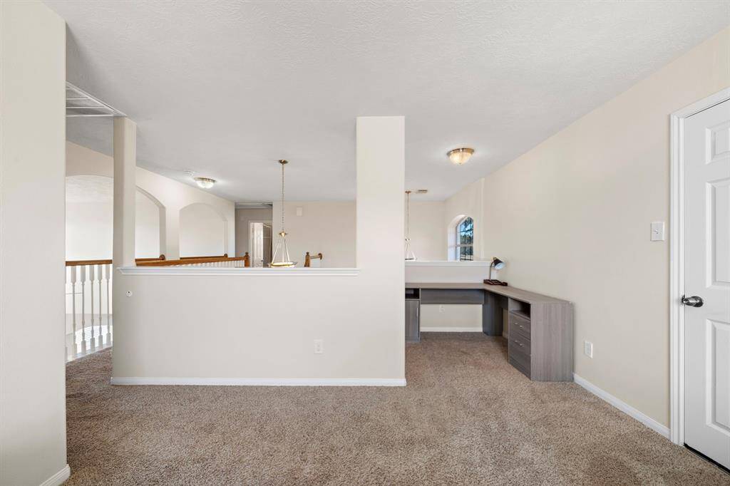 The versatile loft area offers a built-in desk and plush carpeting, perfect for a home office or study nook. Overlooking the living space below, it benefits from natural light streaming through well-placed windows, creating an inviting environment for work or relaxation.