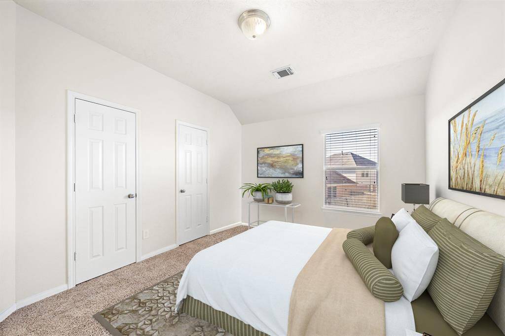 The secondary bedroom is well-lit with a large window providing a peaceful view of the surroundings. Neutral tones and soft carpeting enhance the inviting ambiance, creating a comfortable retreat. Two closets offer ample storage, ensuring functionality and convenience.