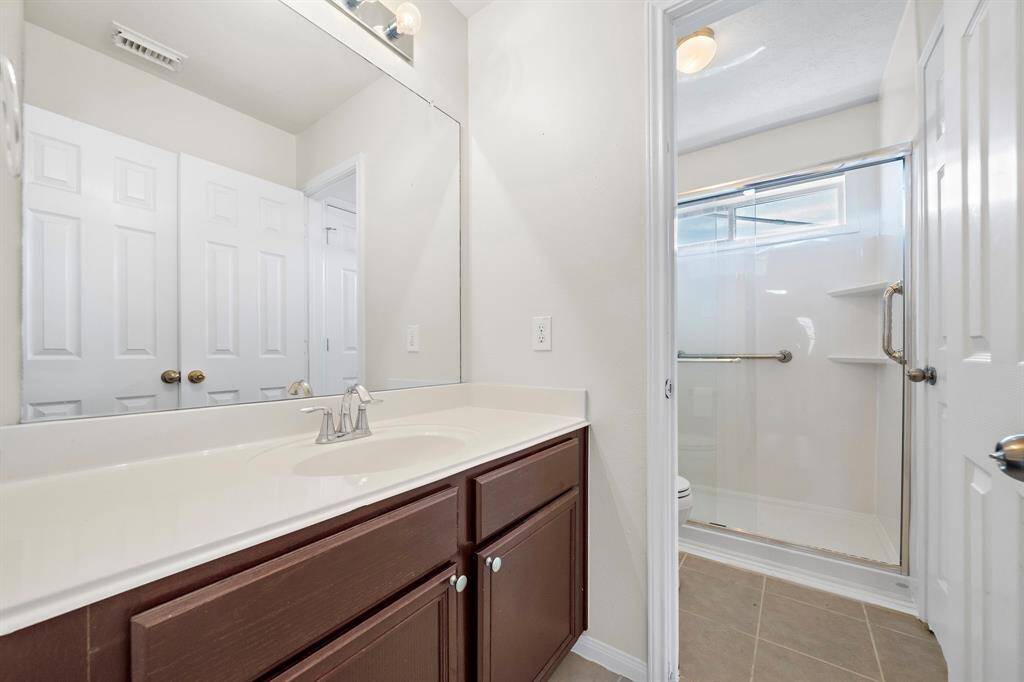 The secondary bathroom presents a bright and functional design, featuring a spacious vanity with ample counter space. The walk-in shower with a sleek glass door adds modern sophistication, while the neutral palette creates a fresh and inviting atmosphere for daily use.