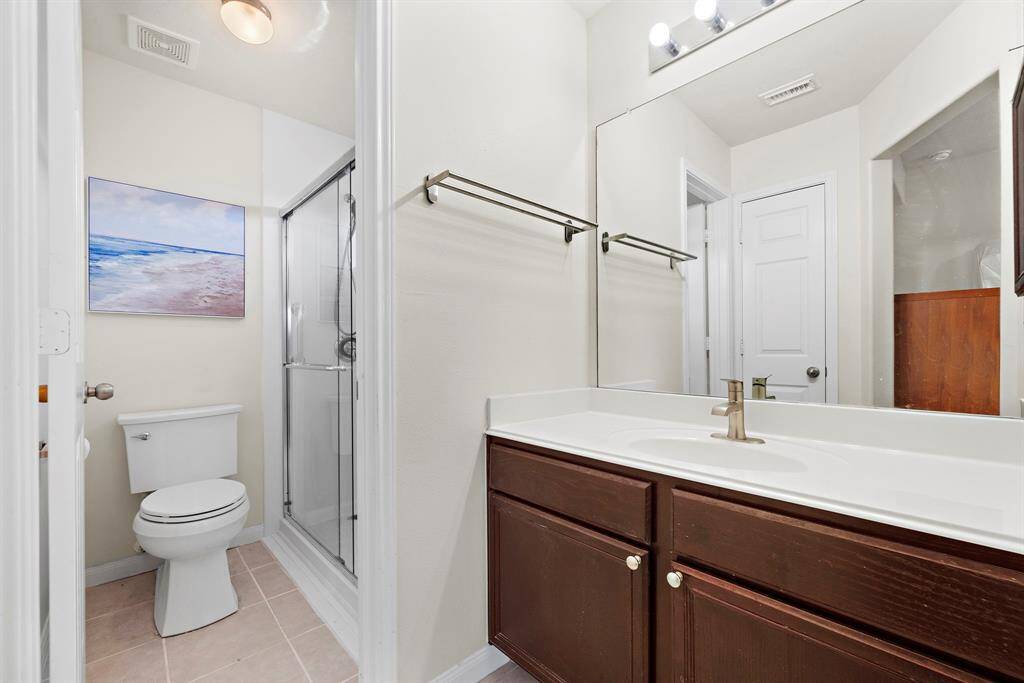 The secondary bathroom offers simplicity and functionality with a clean vanity featuring ample counter space. The efficient walk-in shower with a glass door provides a refreshing touch, while soft, neutral tones contribute to a welcoming, modern ambiance.