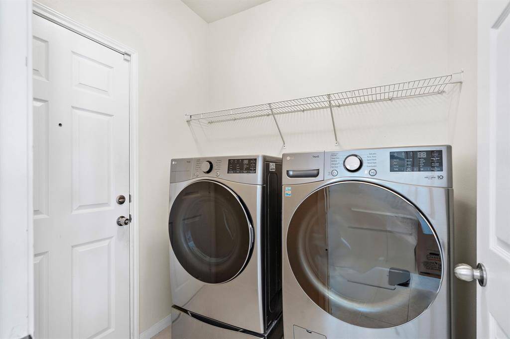 The dedicated utility room offers practicality with its modern washer and dryer, providing efficiency for laundry tasks. A wire shelf above ensures additional storage for cleaning supplies and essentials, enhancing the room's functionality.