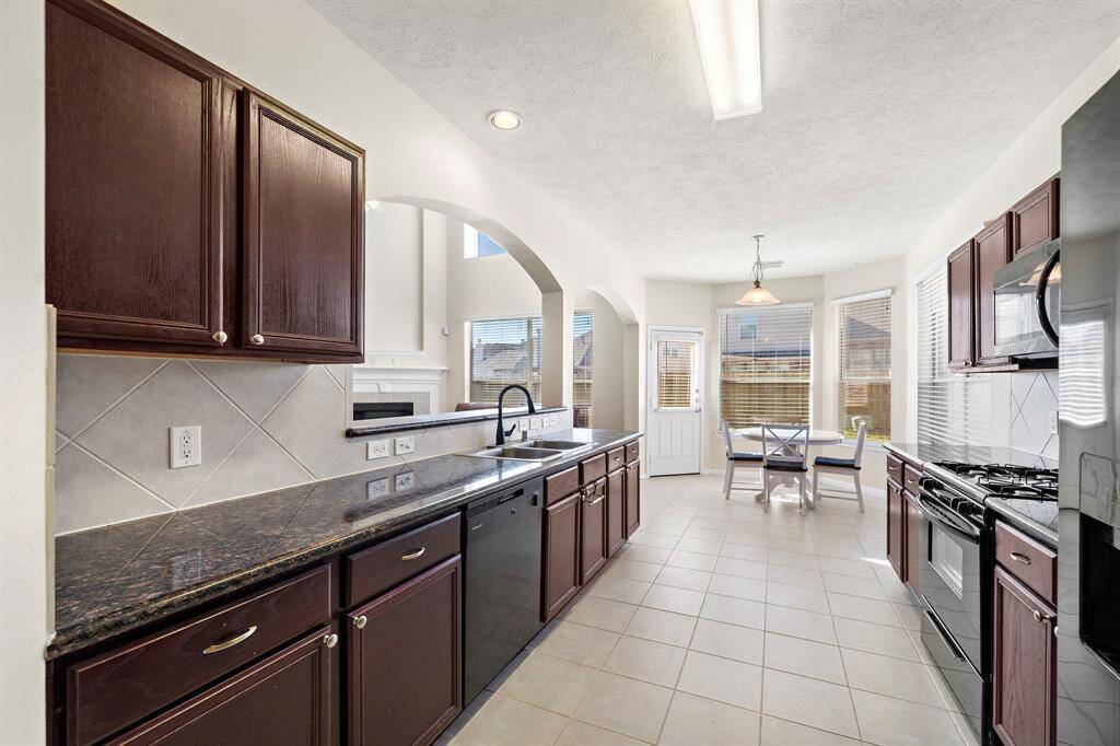 The kitchen offers modern convenience with stainless steel appliances, granite countertops, and a gas range. Expansive cabinetry and a spacious walk-in pantry provide ample storage, while the breakfast bar overlooks the dining area, perfect for casual meals.