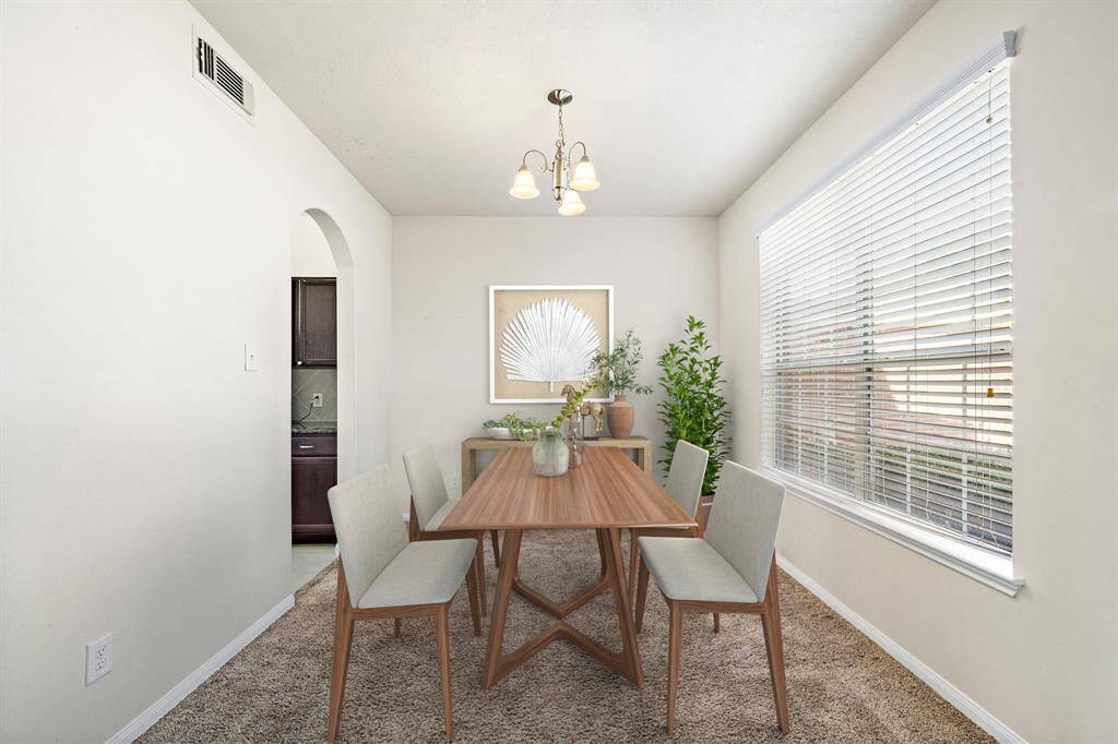 The dining area features a modern, minimalist design with ample natural light streaming through large windows. Neutral tones and sleek furnishings create an inviting space for family gatherings or intimate meals, seamlessly connected to the kitchen for easy access and convenience. This photo has been virtually staged.