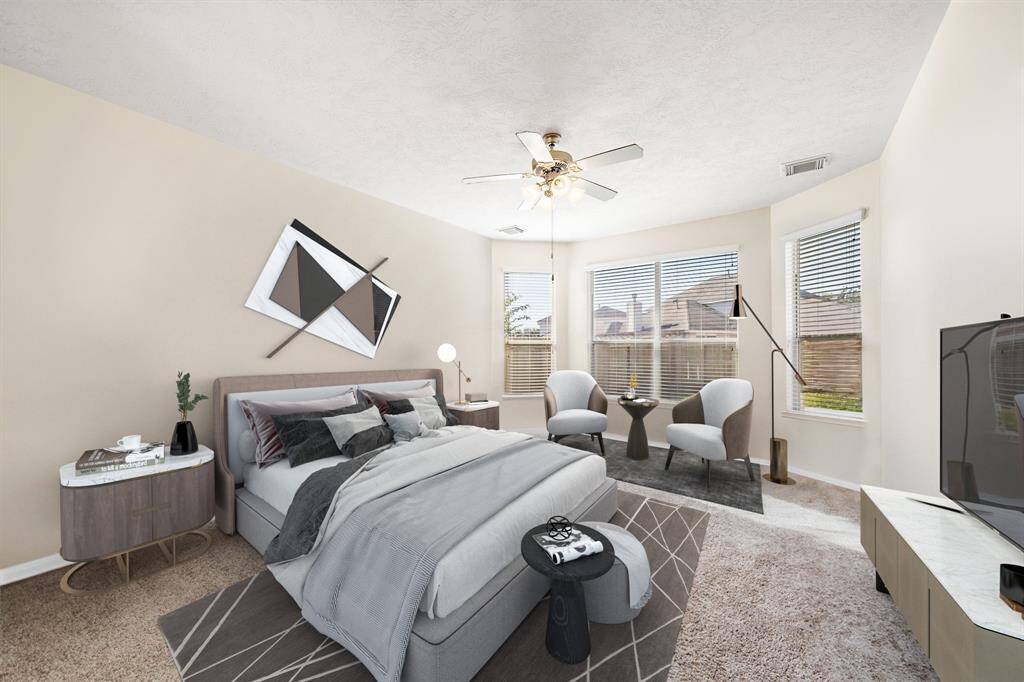 The primary suite on the first floor offers a spacious retreat, featuring large windows that fill the room with natural light. The expansive walk-in closet provides ample storage, while the room's neutral tones and modern decor create an inviting atmosphere for relaxation and comfort. This photo has been virtually staged.