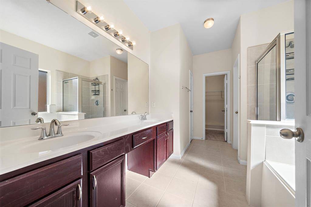 The primary bathroom is a luxurious retreat featuring dual vanities and a soaking tub, perfect for relaxation. A glass-enclosed shower enhances the space with modern sophistication, complemented by tasteful fixtures and finishes.