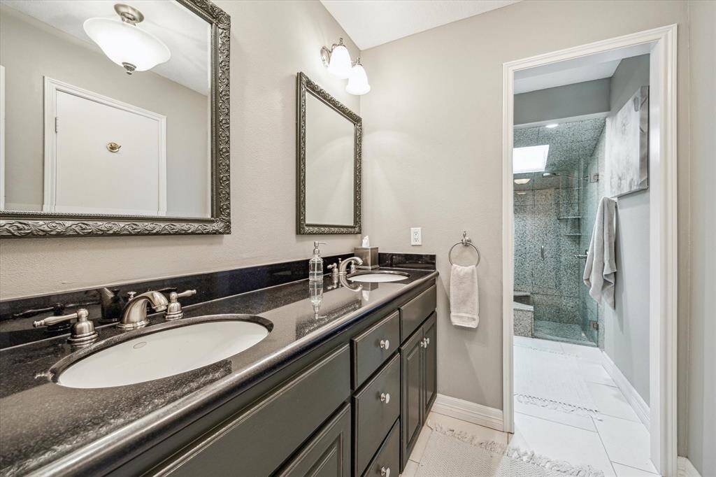 The primary bathroom features dual sinks, plenty of under sink space, and tile flooring. *In 2022, all the plumbing and plumbing fixtures were replaced. *per seller