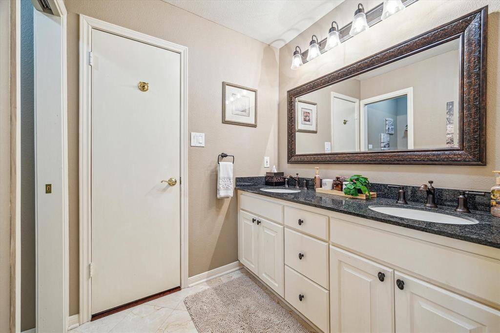 The secondary bathroom features tile floor, under sink storage, and dual sinks.