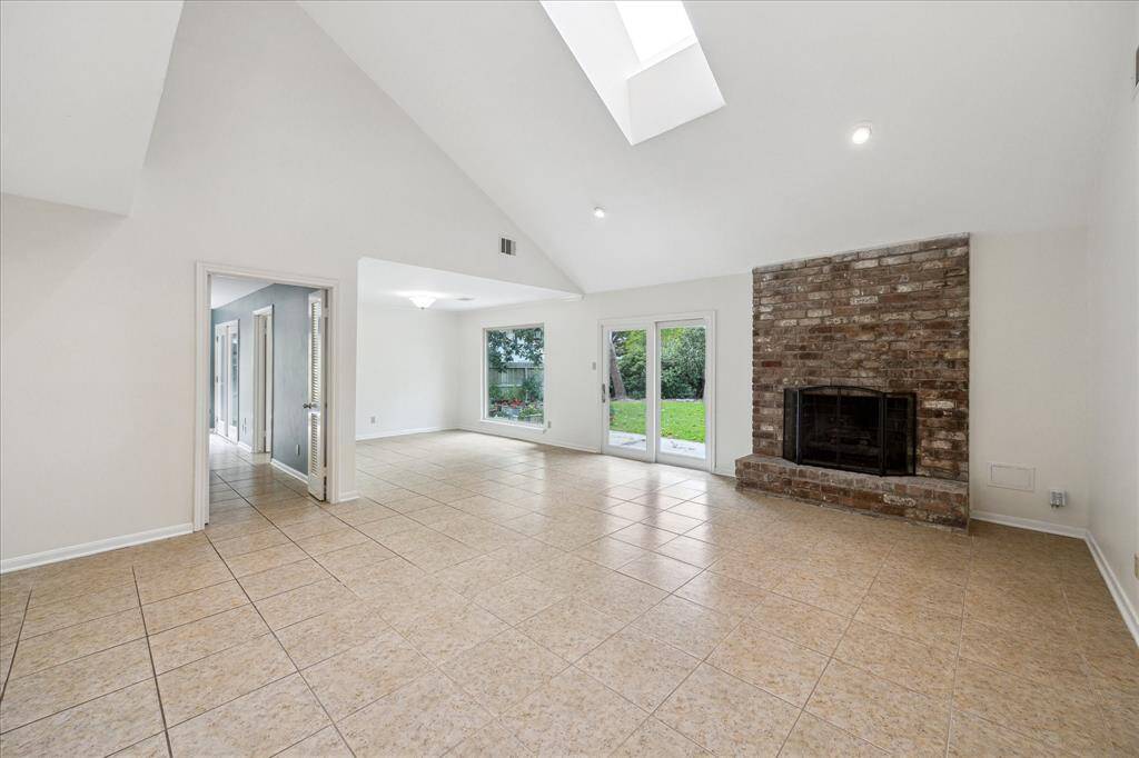 The living room offers soaring ceilings, natural light, and a beautiful fireplace