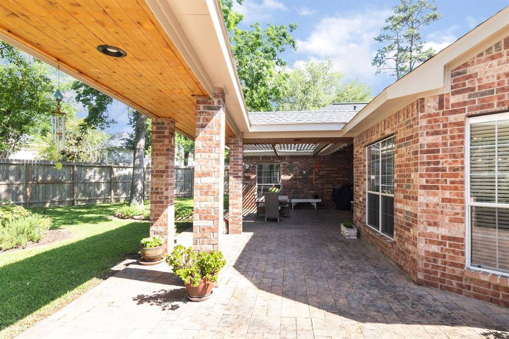 HERE is the backyard. The owners have paid much attention to the outdoor patio space. The breezeway ceiling is lined with gorgeous stained wood and the entire patio space is pavestones. There's a metal gate separating the entry from the driveway to the backyard and patio space.