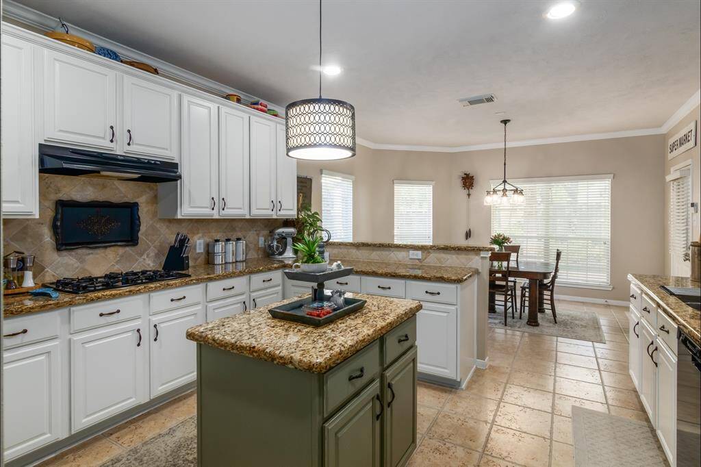 Here is the kitchen view from the dining room opening. So many cabinets, drawers and counterspace. Lovely granite counters and tile backsplash. Gas cooktop, great island, tile floors, pretty lighting! And you can see the breakfast room from this angle.