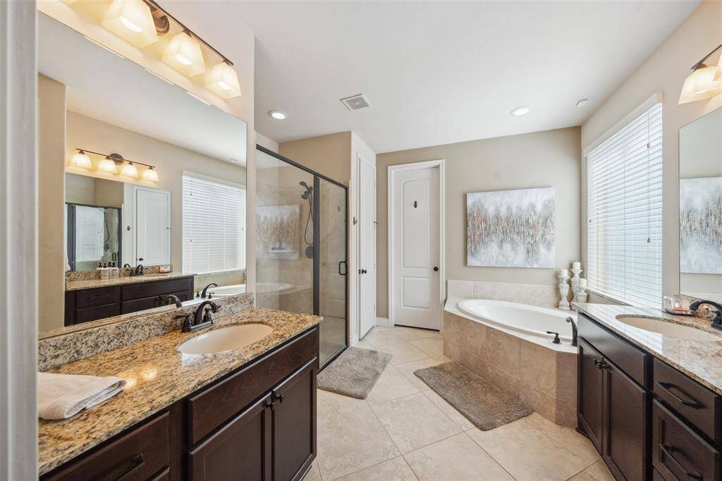Large primary en-suite bath with two separate sink areas, large corner soaking tub and separate shower. The primary closet, just beyond, is large and features built-in shelves.
