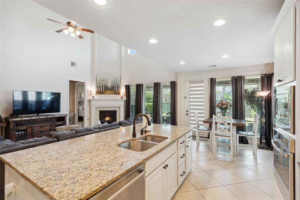 Large center island with sink and dishwasher. Breakfast area beyond is surrounded by windows for natural light.