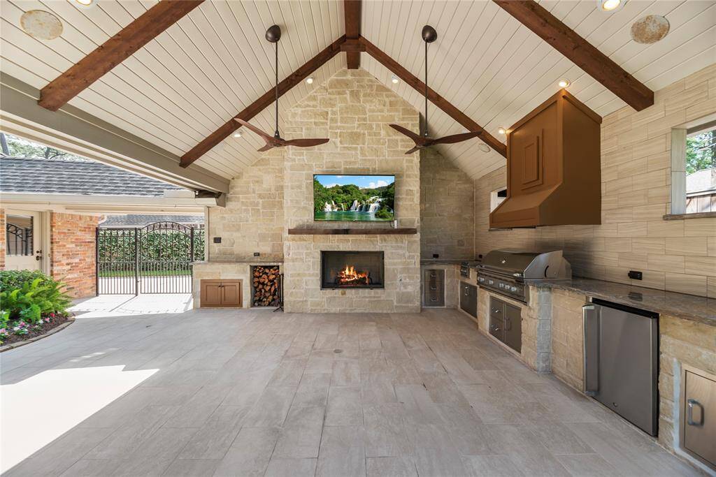 A beautiful view of the architectural detail and character of the outdoor kitchen with sleek stone finishes, expansive Onyx countertops, wood storage, and a wood-burning fireplace for year-round enjoyment.