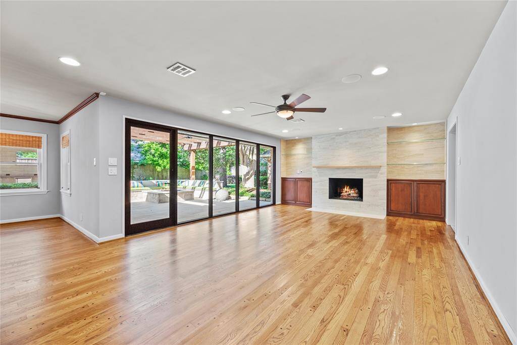 Spacious and inviting living area featuring rich hardwood floors, a sleek modern fireplace with built-ins, and open views of the beautiful patio—perfect for indoor-outdoor entertaining.
