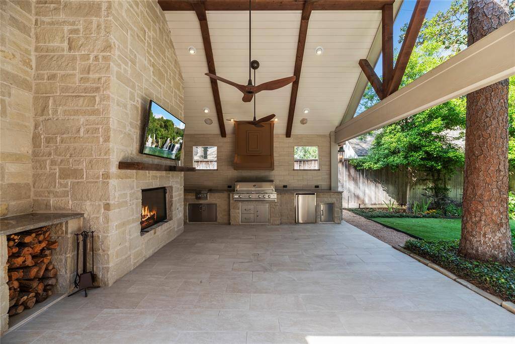 The outdoor entertainment area continues under the spacious covered patio area with vaulted ceiling, a wood burning stone fireplace, mounted TV, and a fully equipped summer kitchen featuring built-in grill and stainless appliances, and kept cool under the Big Ass Fans. Enjoy the outdoors peacefully benefiting from the mosquito misting system!